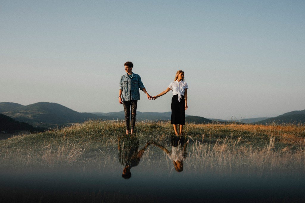 Young couple holding hands and looking away from each other in the countryside