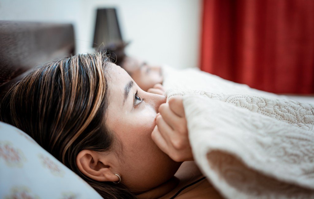 A woman hiding under a blanket