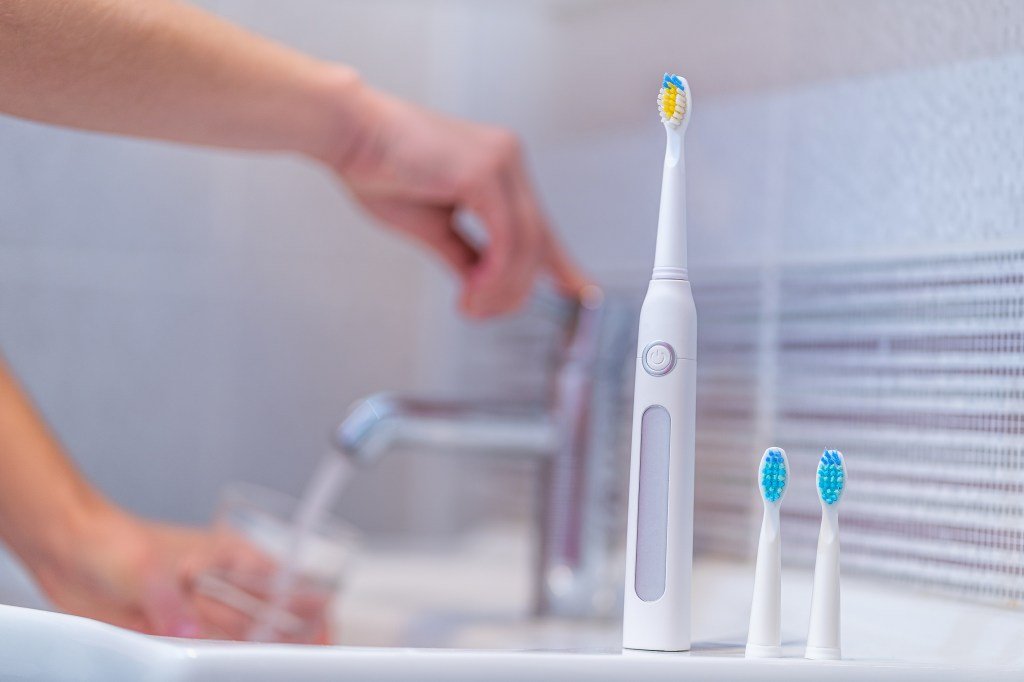 Electric toothbrush, replacement brush head in bathroom.