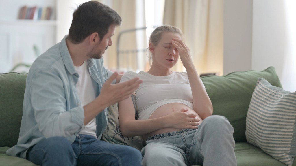 A pregnant woman quarreled with her husband on the sofa.