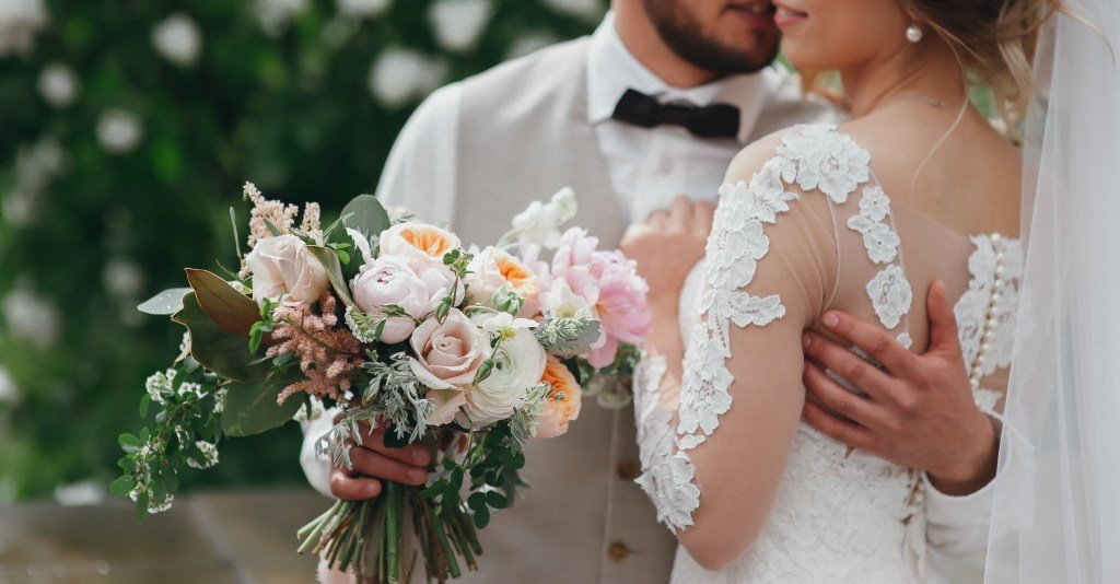Bride and groom holding bridal bouquet.