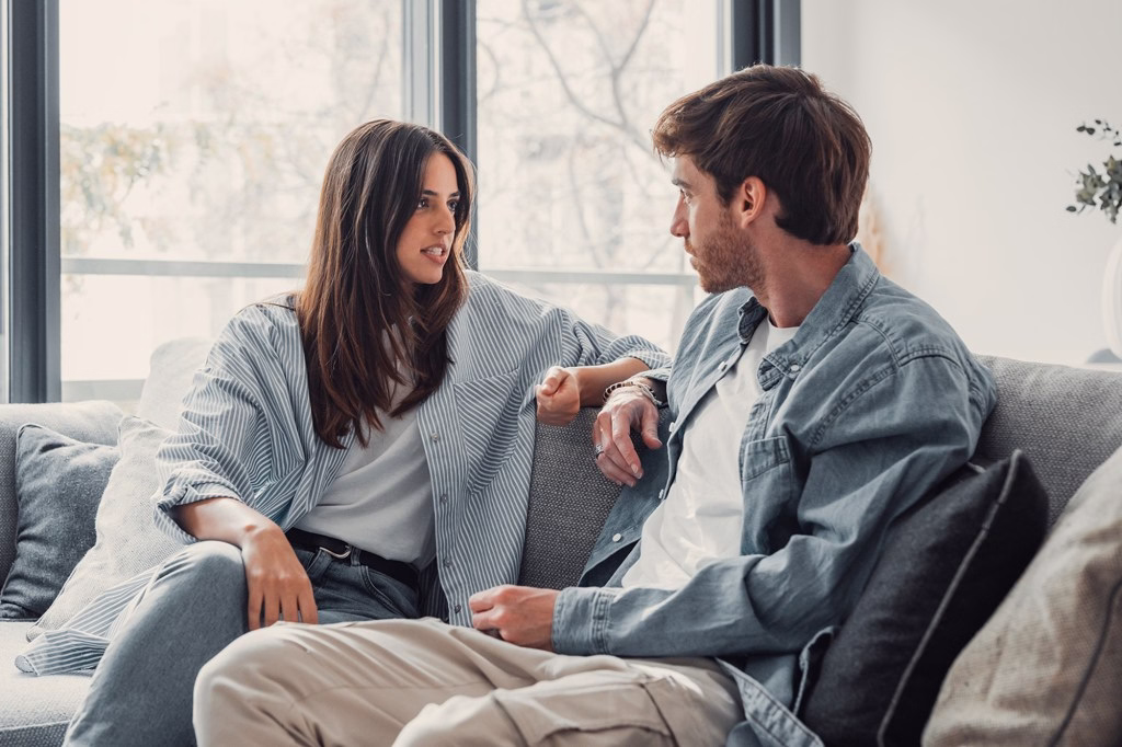 A couple was sitting on the sofa having a heated discussion.